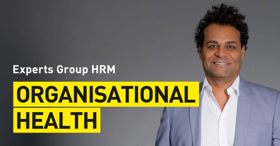 Lächelnde Person im Anzug vor grauem Hintergrund, Text „Organisational Health“